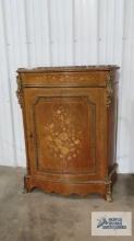 Antique marble top cabinet with floral motif and carved metal corners. 43-1/2 in. tall by 35 in.