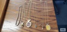 Gold colored costume jewelry necklaces with various pendants including one with geode and other